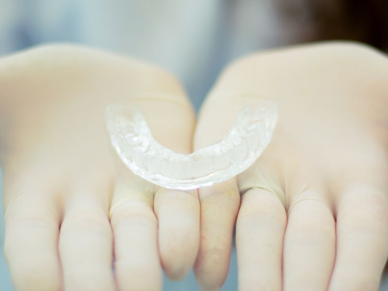 Custom dental retainer held by gloved hands at Englewood Dentistry